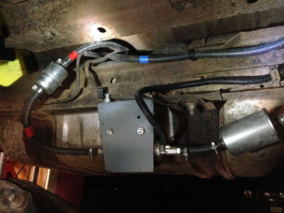 Underbody view of fuel lines, filters, and a metal box installed on a vehicle