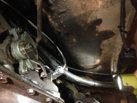 1979 Ford Bronco - Close-up view of the transmission linkage and associated cables on a vehicle's undercarriage.