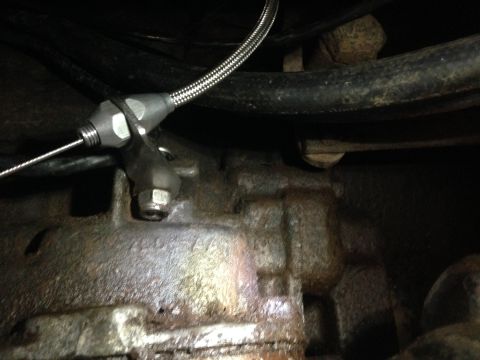 1979 Ford Bronco - Close-up view of a throttle cable linkage mechanism connected to a vehicle's transmission.