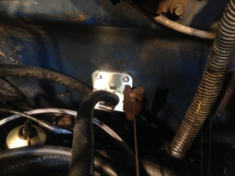 1979 Ford Bronco - Close-up of a bracket being installed in an engine bay, with visible hoses and wiring.