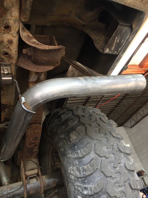 1979 Ford Bronco - Underside view of a vehicle's exhaust system and tire, showing significant rust on the chassis components.