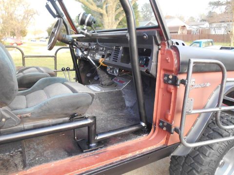 1972 Ford Bronco - The interior of a Ford Bronco shows custom roll cage and seats, with the exterior visible on the right.