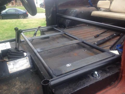 1972 Ford Bronco - The interior of a vehicle shows a roll cage structure and a prominent gear shifter, with a glimpse of the exterior through the window.