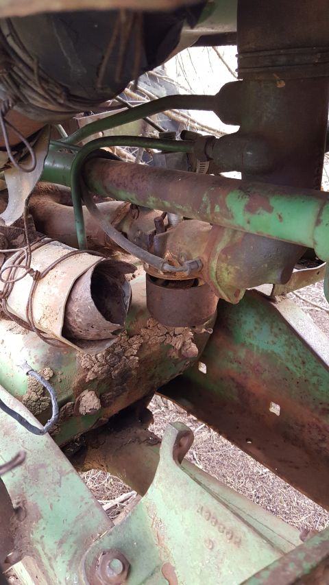 1973 Ford F-100 - Close-up view of weathered green and rusty tractor mechanical parts, including hydraulic lines and wiring.