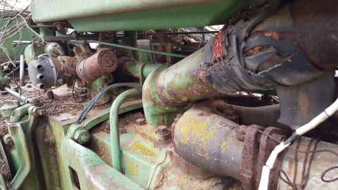 1973 Ford F-100 - Engine components of a green tractor, showing signs of rust and wear.