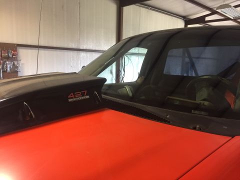 1982 Ford Bronco - A black hood scoop with "427" badging is visible on the orange hood of a vehicle.