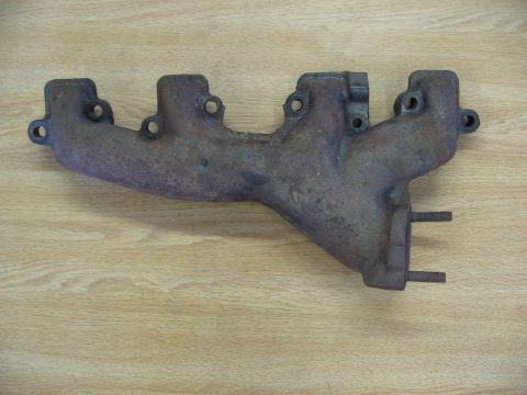 1968 Mercury Cougar - This exhaust manifold, shown on a wooden background, is a component for a vehicle's engine system.