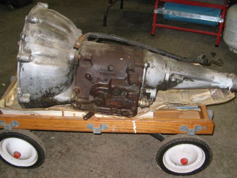 1968 Mercury Cougar - An automatic transmission, likely from a classic car, is shown resting on a small wooden cart.