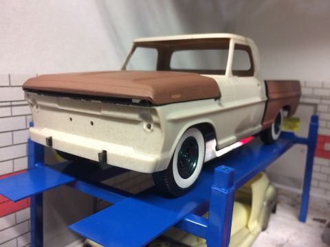 1989 Ford Bronco - A model of a 1967 Ford F-Series truck is shown on a blue lift, with another model vehicle visible below.