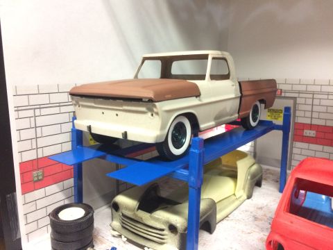 1989 Ford Bronco - A model of a 1967 Ford F-Series truck is shown on a blue car lift with other models around it.