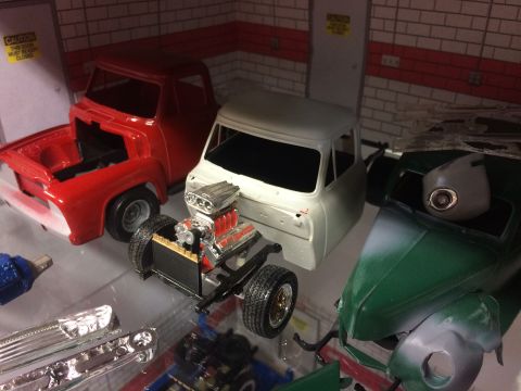 1989 Ford Bronco - Several model car components and partially assembled vehicles are displayed on a shelf.