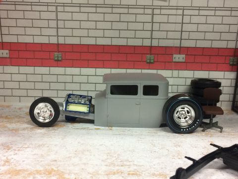 1989 Ford Bronco - Unfinished model car with a visible engine and chrome wheels sits in a garage setting.