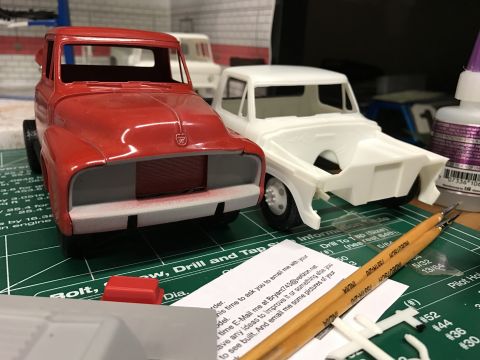1989 Ford Bronco - Model truck kits are being assembled on a craft mat with various tools and supplies nearby.