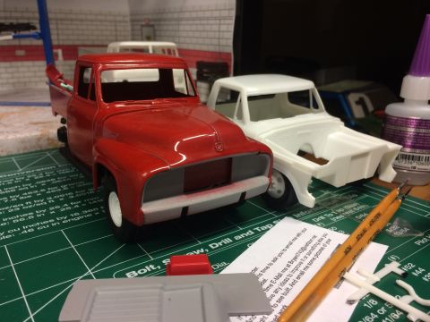1989 Ford Bronco - Two model trucks, one red and one white, are displayed on a craft mat with various modeling tools and supplies.