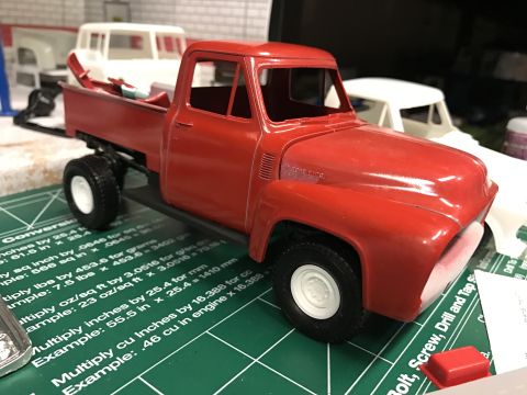 1989 Ford Bronco - Model of a 1956 Ford F-100 pickup truck in red, seen from a 3q-front angle, with other unpainted models in the background.