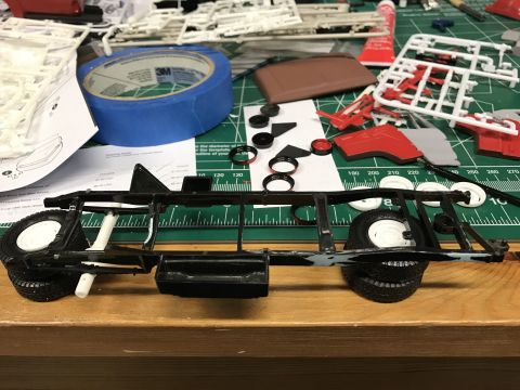 1989 Ford Bronco - Model car assembly in progress, showing chassis, wheels, and unassembled parts on a workbench.