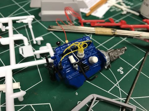 1989 Ford Bronco - Model engine assembly on a cutting mat surrounded by unassembled model kit parts.