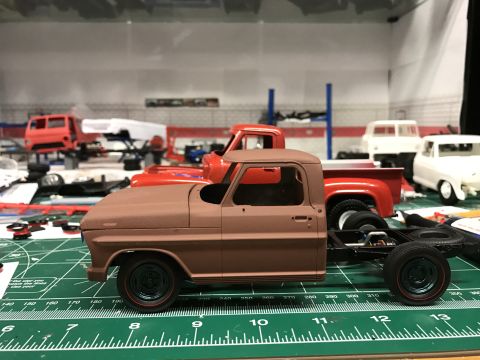 1989 Ford Bronco - A partially assembled model truck sits on a workbench, surrounded by other unfinished vehicle models.