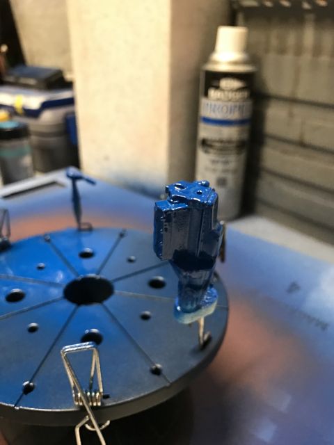 1989 Ford Bronco - A blue painted model engine part is mounted on a turntable, likely for painting or detailing, with a can of spray paint visible in the back…