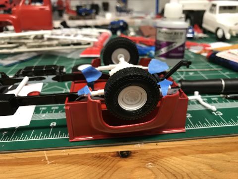 1989 Ford Bronco - A partially assembled model truck chassis is shown on a cutting mat with various parts and glue in the background.