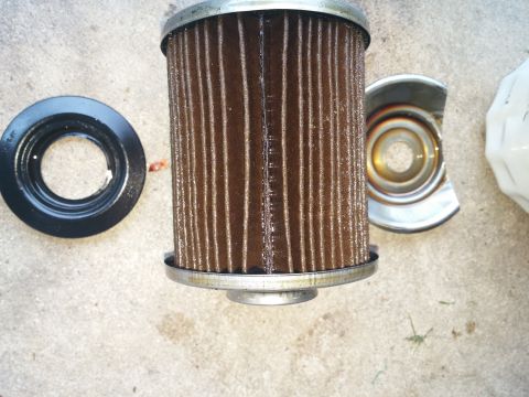 2000 Ford Crown Victoria - A used oil filter and its gasket are shown disassembled on a concrete surface.
