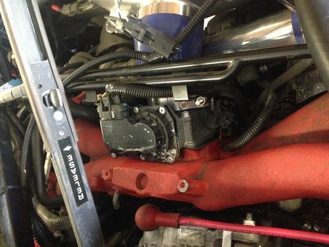 2015 Subaru Impreza - Close-up view of an engine component, likely a throttle body, attached to a red intake manifold.