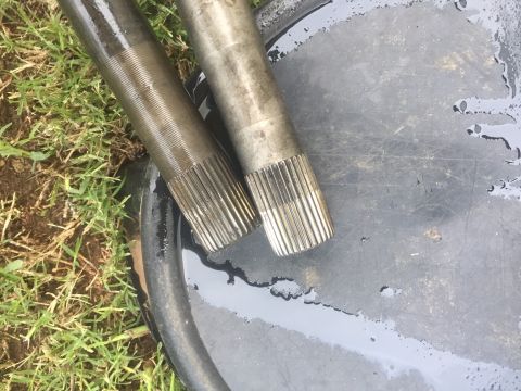 1982 Ford Bronco - Close-up of two splined metal shafts, possibly automotive parts, on a wet surface.