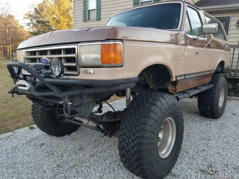 1988 Ford Bronco - This lifted Ford Bronco features large off-road tires and a custom front bumper with a winch.