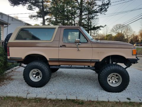 1988 Ford Bronco - This lifted SUV features a two-tone brown paint scheme and aggressive off-road tires, suggesting a model year around 1987 based on its body…
