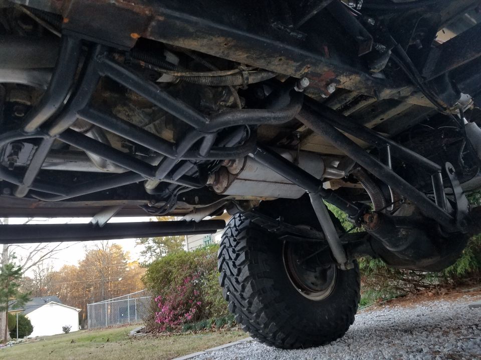 Underside view of a lifted SUV with aftermarket roll cage and large tires