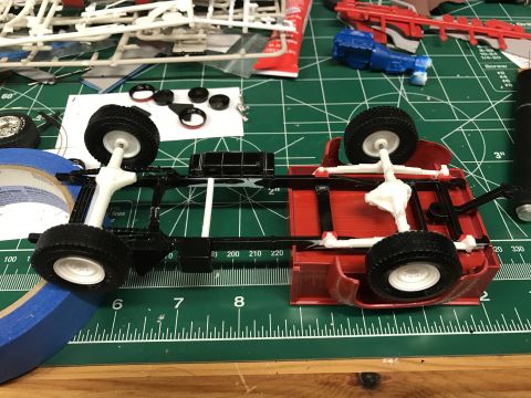 1989 Ford Bronco - The underside of a model truck chassis is shown, with parts and tools scattered around.