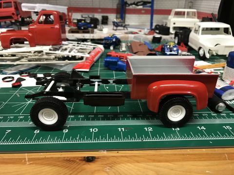 1989 Ford Bronco - Model truck assembly in progress with multiple unfinished vehicles and parts visible.