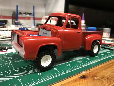 1989 Ford Bronco - A red model truck is partially assembled on a craft mat, with its hood open.
