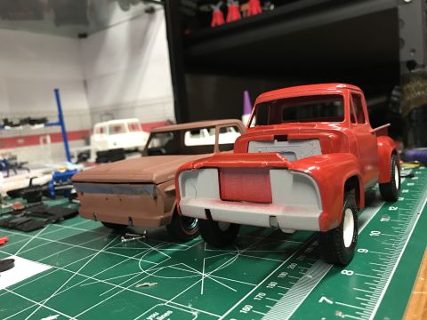 1989 Ford Bronco - Two model trucks, one red and one brown, are partially assembled on a green cutting mat with rulers.