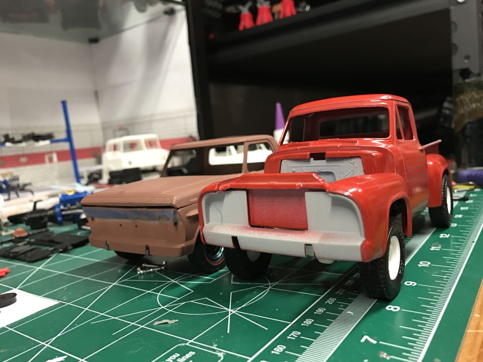 Red and brown model trucks on a green cutting mat