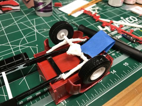 1989 Ford Bronco - A model truck chassis is being assembled on a cutting mat with various tools and parts nearby.
