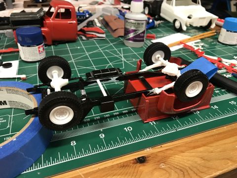 1989 Ford Bronco - A model truck chassis is shown on a cutting mat, surrounded by hobby supplies, indicating it is part of a build project.