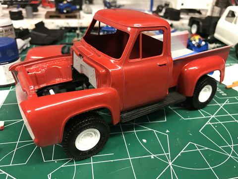 1989 Ford Bronco - A partially assembled red 1953 Ford F-100 model truck sits on a cutting mat, ready for further detailing.