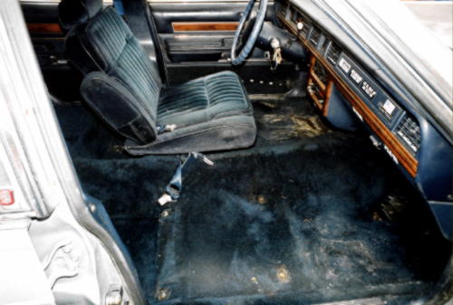 Blue cloth interior of a full-size sedan viewed through the open passenger door