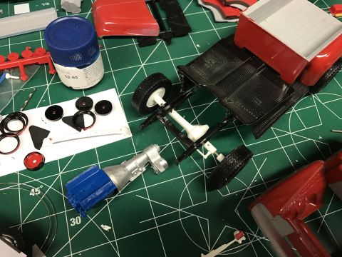 1989 Ford Bronco - Hobbyist assembling a model vehicle, with parts and tools spread across a cutting mat.