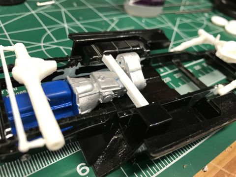 1989 Ford Bronco - A model car's chassis is shown with its engine and transmission components being assembled on a green cutting mat.