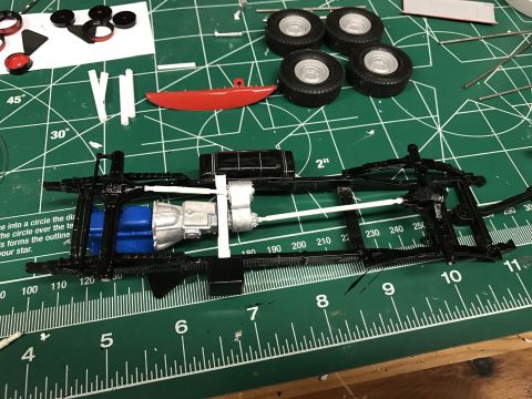 1989 Ford Bronco - Model car chassis assembly in progress, with wheels and other parts laid out.