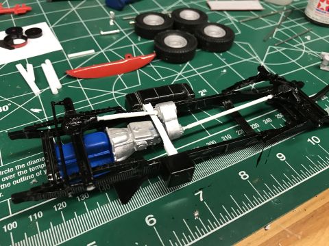 1989 Ford Bronco - Model car chassis assembly in progress on a cutting mat with various parts and tools.