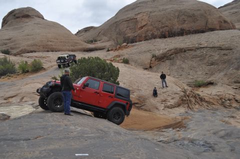 1991 Ford Bronco - Two Jeeps navigate a challenging off-road course in a desert landscape.