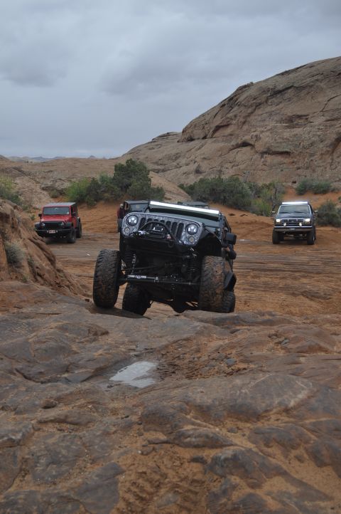 1991 Ford Bronco - Multiple Jeeps navigate a challenging rocky terrain in a desert landscape.