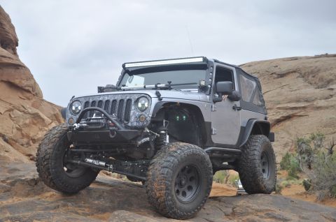 1991 Ford Bronco - This modified Jeep Wrangler JK is navigating a rocky off-road trail under a cloudy sky.