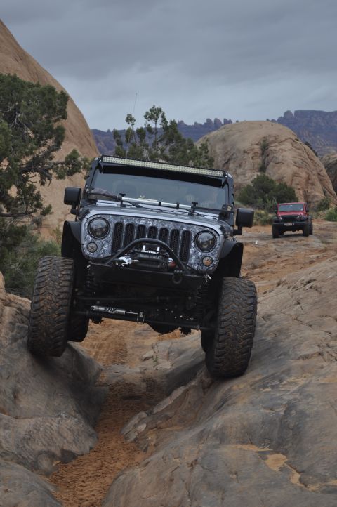 1991 Ford Bronco - A Jeep Wrangler tackles a challenging rocky path with another Jeep visible in the background.