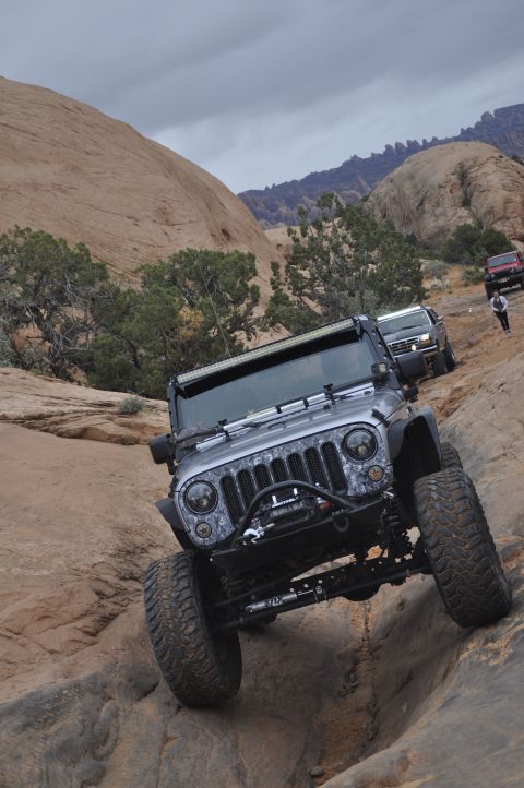 1991 Ford Bronco - Modified Jeep Wrangler navigating a difficult rocky trail with other vehicles present.