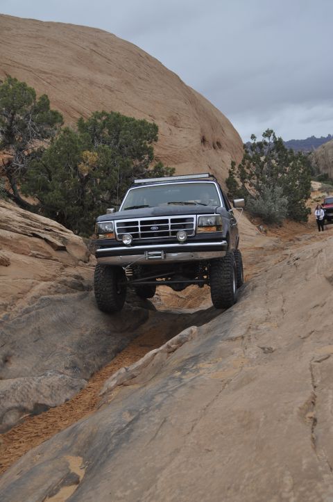 1991 Ford Bronco - Ford Bronco navigating a challenging rocky off-road course in a desert landscape.