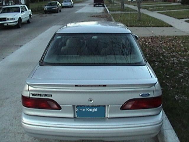 1995 Ford Taurus rear view, parked on street with other cars visible